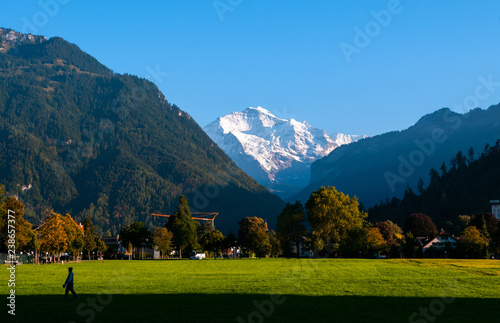 Peolpe in green field Hohematte park and Swiss alps in Interlaken, Switzerland