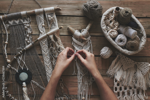 Female hands weaving macrame on a wooden table. Do it yourself. Top view.