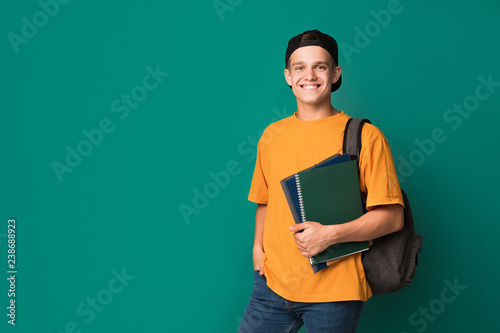 Teen guy with books and backpack over background