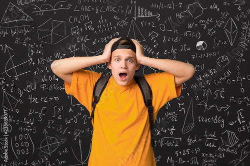 Shocked student standing by blackboard with math formulas