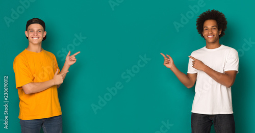 Friendly teen boys pointing on copy space