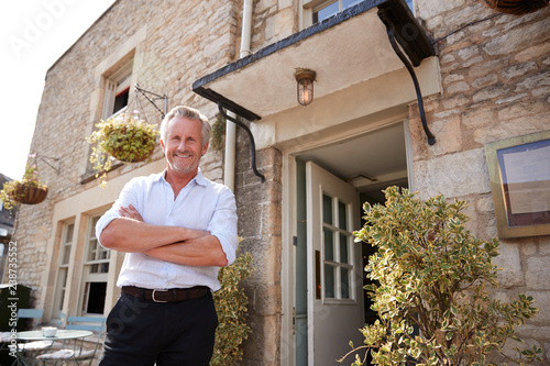 Senior male restaurant pub owner stands outside the entrance