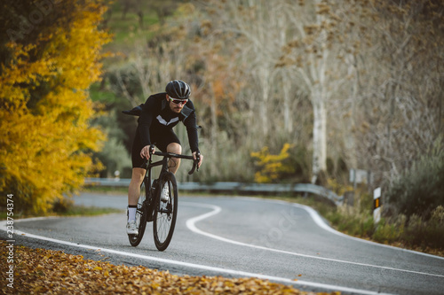 Professional road bicycle racer in action. Men cycling mountain road bike at sunset.