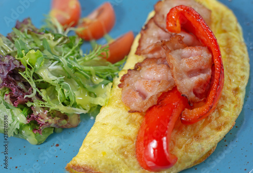 Omelet with tomatoes, mushrooms and bacon. Breakfast on blue background.