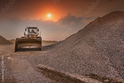 Excavator in a quarry of stone transformation in gravel for the construction of a road