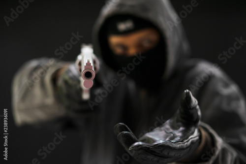 Robber with a gun robbing intimidate.Crime and robbery concept.