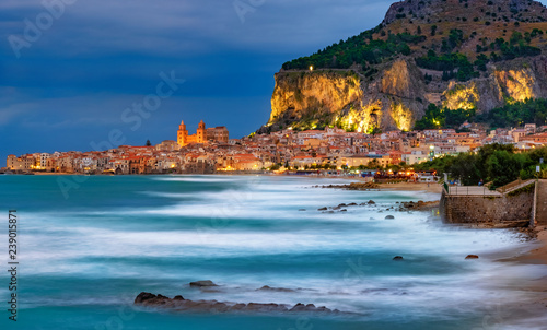 Cefalu town on the coast of Sicily island with blurry sea surface and illuminated mountain in Sicily island, Italy