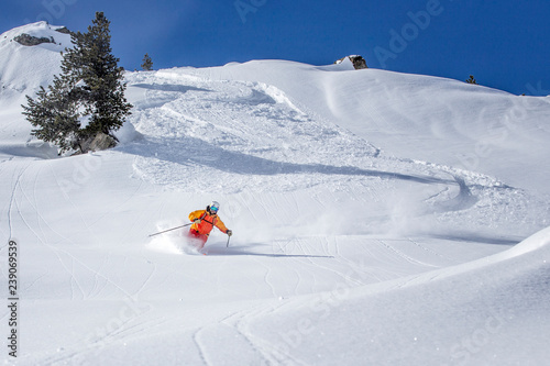 freeride skier skiing downhill through deep powder snow