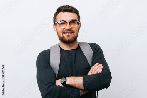 Cheerful hipster man waring a backpack and crossing hands