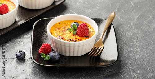 Creme brulee. Traditional French vanilla cream dessert with caramelised sugar on top and fresh berry. - Image