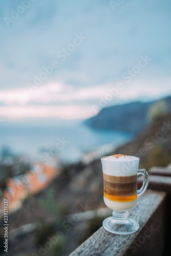 Barraquito, traditional coffee variety of Tenerife on background of ocean and harbor Los Gigantes, Canary Islands, Spain