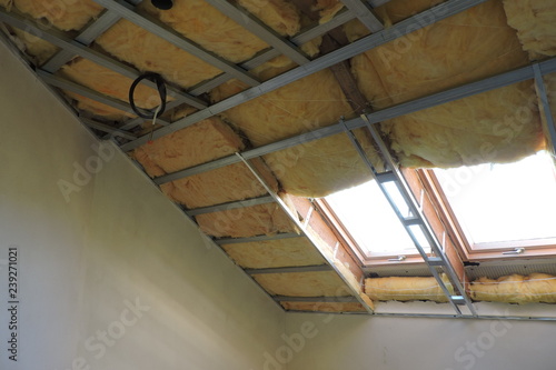 A room with a metal frame of a ceiling under construction insulated with mineral wool 