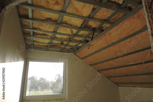 A room with a metal frame of a ceiling under construction insulated with mineral wool 