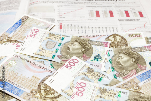 Plik banknotów 500 PLN na tle wykresów i słupków