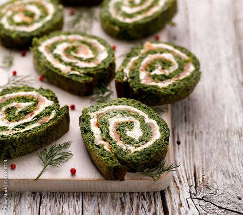 Spinach roulade stuffed with cream cheese and smoked salmon sliced on a white board. Delicious appetizer, party food