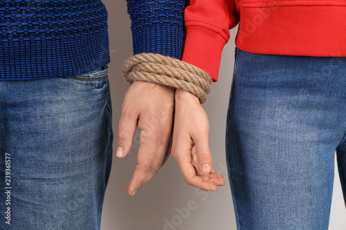 Couple with tied together hands on light background. Concept of addiction