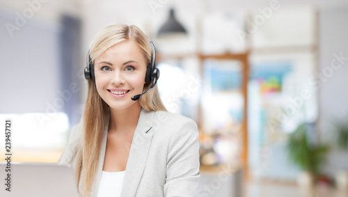 business, technology and communication concept - female helpline operator in headset working at office
