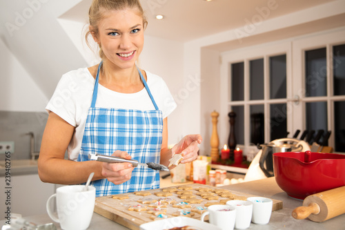 junge blonde Frau backt in der Küche Pläzchen Keckse für Weihnachten