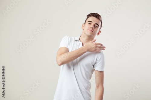 Indifferent guy dressed in a white t-shirt and jeans is on a white background in the studio