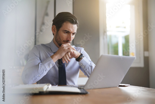 Handsome businessman concentrating on laptop in modern office