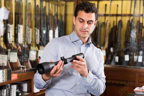 Adult male owner of hunting shop checking optical sights