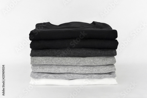 stack of folded black, grey and white color (monochrome) t-shirt on white background