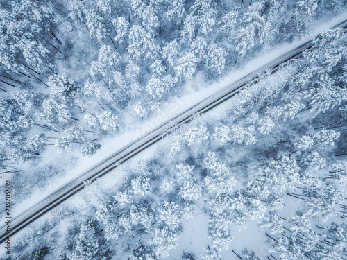 Aerial view of winter road and cars passing by forest in mountains. drone shot