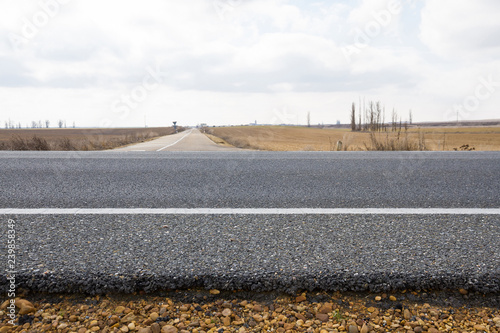 Vista transversal de la capa de base asfaltica o firme con graba y asfalto de una carretera a ras del suelo en el cruce con otra 