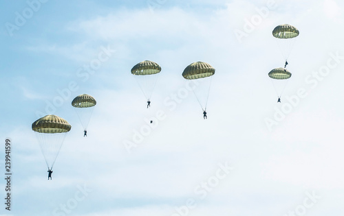 Many soldiers with parachutes in the sky.