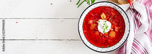 Traditional Ukrainian Russian borscht with white beans on the bowl. Beetroot soup. Plate of red beet root soup borsch on white table. Traditional Ukraine food cuisine. Banner. Top view