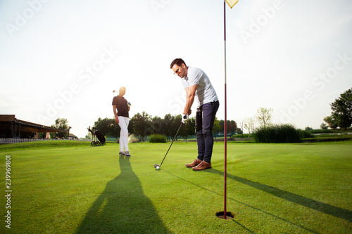 Young sportive couple playing golf on a golf course - Image