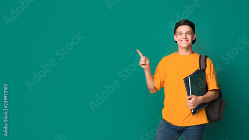 Teen student with books pointing on copy space