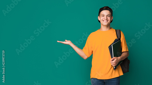 Happy student with books holding something on palm