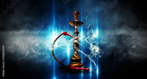 Dark blue background of smoking hookah on the concrete floor, in clouds of smoke and neon light