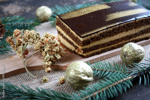 Orzechowe złote ciasto pośród bożonarodzeniowych dekoracji, złotych orzechów, jarzębiny i szyszek