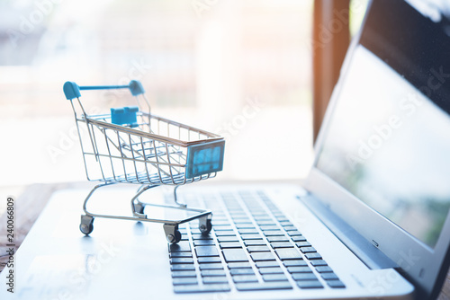 Online shopping concept. Shopping cart with laptop on the desk.