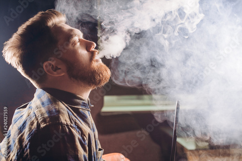 magicical smoking. young man relaxing with hookah. close up side view photo. feeling, emotion. copy space