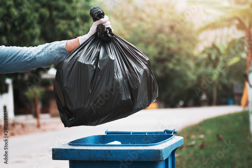 hand holding garbage black bag putting in to trash