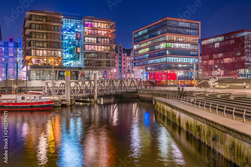 The Harbor District (HafenCity) in Hamburg, Germany, at night. A view of the Sandtorkai and the Magellan-Terassen across the traditional port Sandtorhafen.