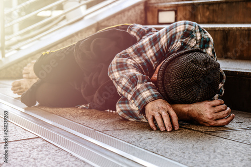 Asian male poor homeless man sleeping on pathway with suffering and sad