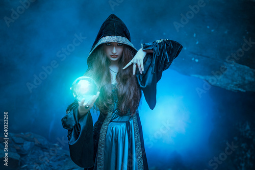 The witch with magic ball in her hands causes a spirits