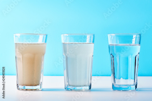 Water filters. Concept of three glasses on a white blue background. Household filtration system.