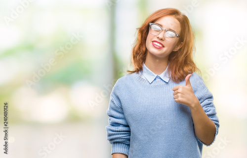 Young beautiful woman over isolated background wearing winter sweater doing happy thumbs up gesture with hand. Approving expression looking at the camera with showing success.