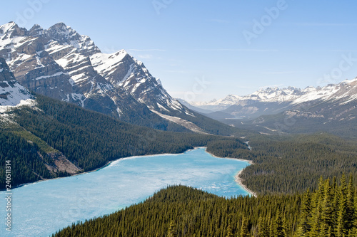 Spring aerial view of the Peyto lake and snowy rocky mountains in background - Banff national park, Alberta, Canada. Shot was taken in late spring and the lake is still half frozen.