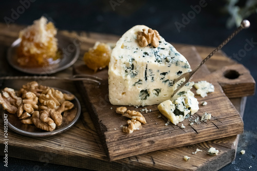 Danish blue cheese on a wooden board with walnut kernels. dark background