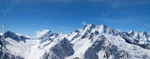 Panorama of snow-capped mountain peaks and beautiful blue sky