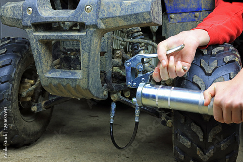 using a grease gun on a quad bike