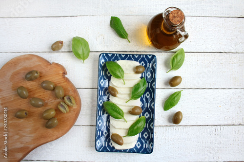 Mozzarella, zielone oliwki, liście bazylii i dzbanek oliwy