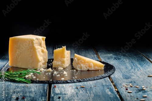 Pieces of parmesan or parmigiano cheese on a wooden dark board