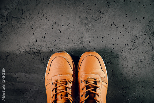 A pair of brown, warm men's shoes on a dark, stone background. Top view for winter, autumn men's shoes, fashion and dress concept for men, businessmen. Shops with footwear.